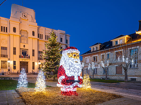 père noël sur une place entouré de sapin