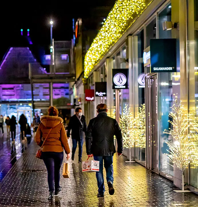 Coupe se promène dans une rie piétonne décorée avec des sapins et guirlandes