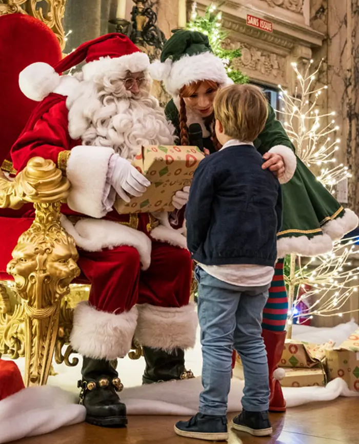 Père noël et lutine donnant un cadeau a une enfant